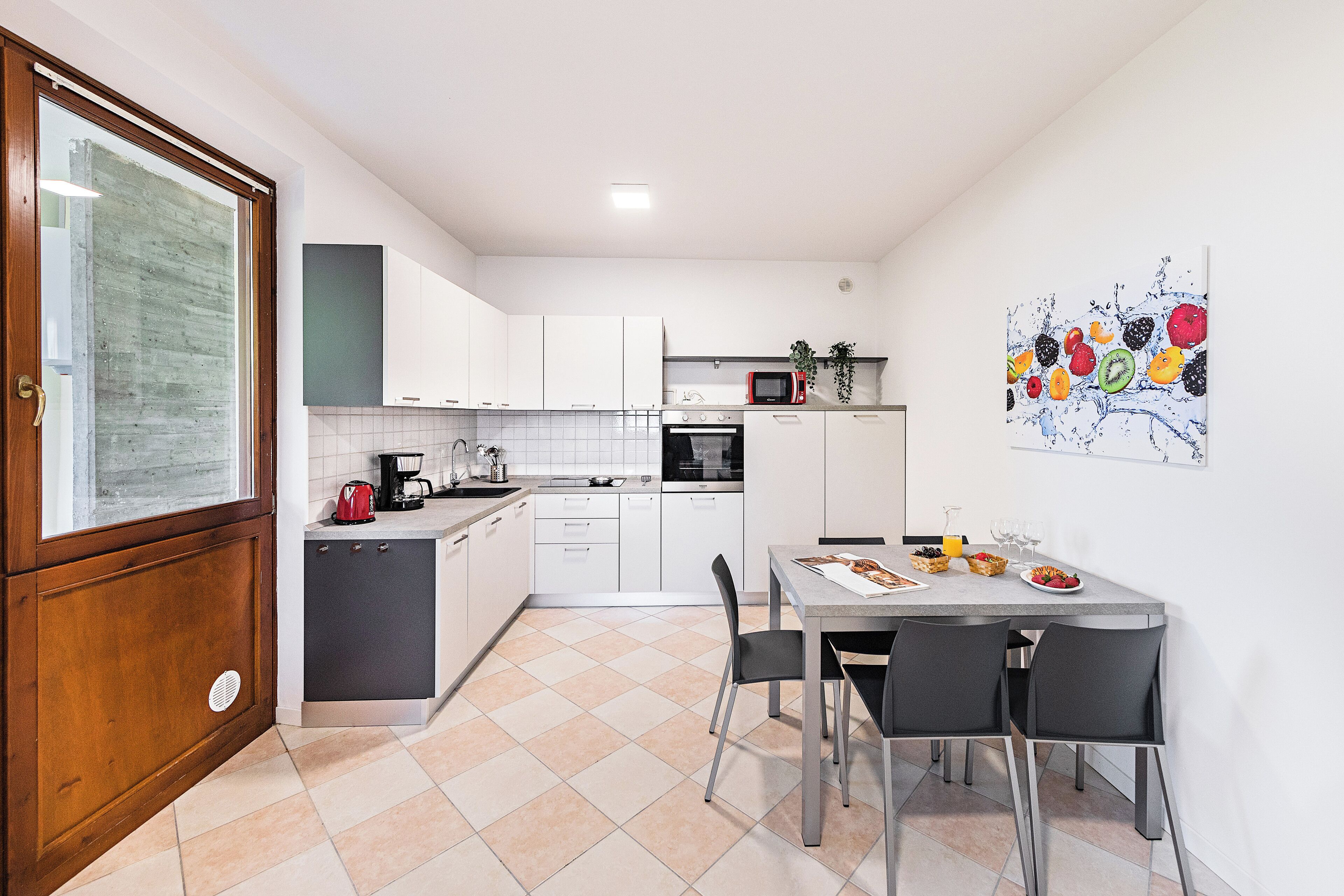 A compact kitchen with white cabinets, a microwave, and a dining area with a table and chairs.