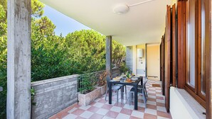 Un patio techado al aire libre con suelo a cuadros, una mesa lista para comer y vistas a zonas verdes.