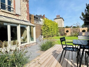 A patio with a wooden deck, black metal chairs, and a table. - The Duplex at 10 Honfleur (Honfleur)