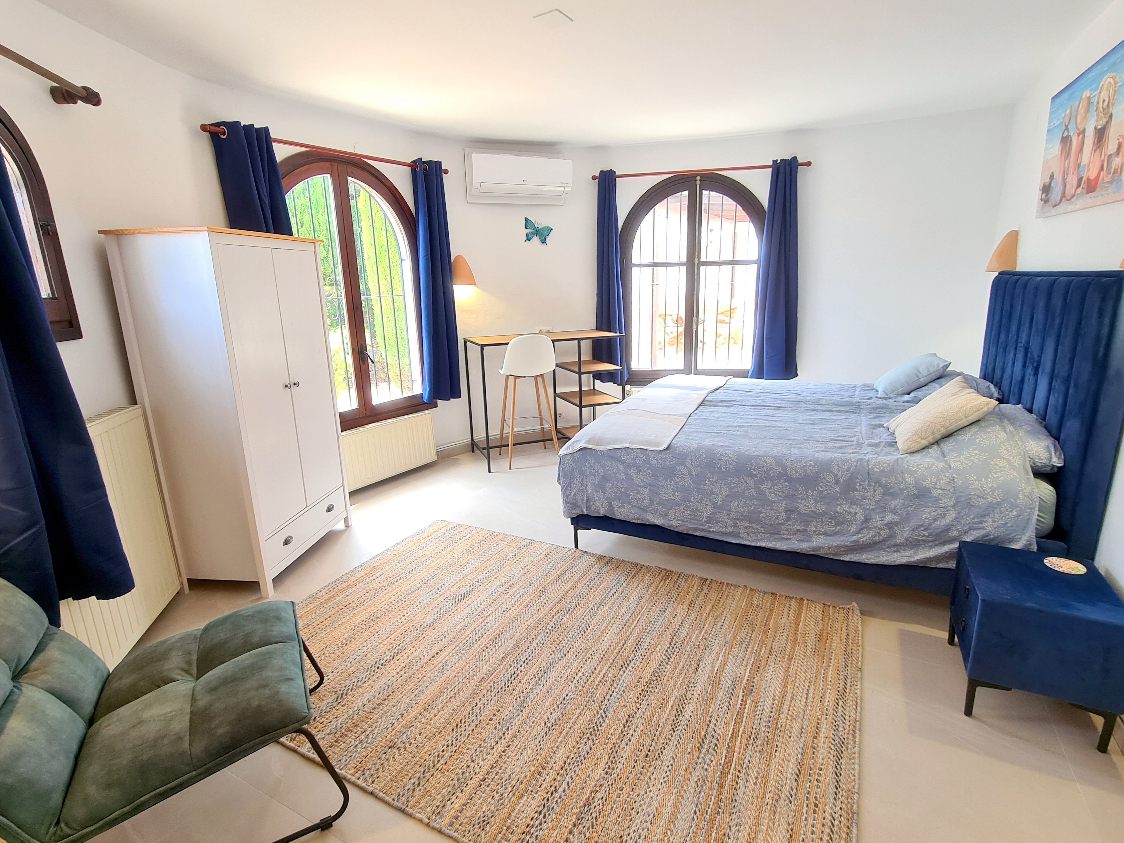 Een slaapkamer met een bed, een bureau, een stoel en een kledingkast.