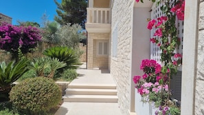 Stroll through lush gardens to a charming building with a traditional facade and inviting balcony.