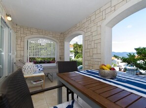 Enjoy a meal on the balcony with a view of lush surroundings and distant buildings.