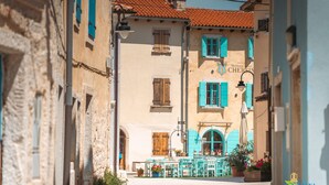 A narrow street with buildings on either side, a Heritage Hotel sign, and outdoor seating with chairs and tables. - Double Room in Fažana - near the Beach (Fažana)