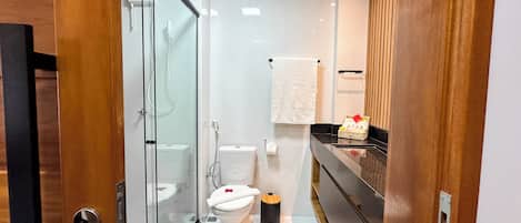 Un baño moderno con cabina de ducha de vidrio, inodoro y tocador con perchero.
