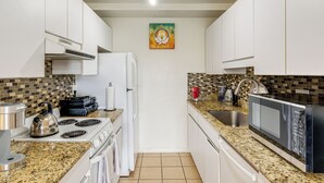 A kitchen with white cabinets, a granite countertop, a stove, a refrigerator, a microwave, and a sink. - Condo Near Hospitals & 1/2 Mi to Mission Bay! (San Diego)