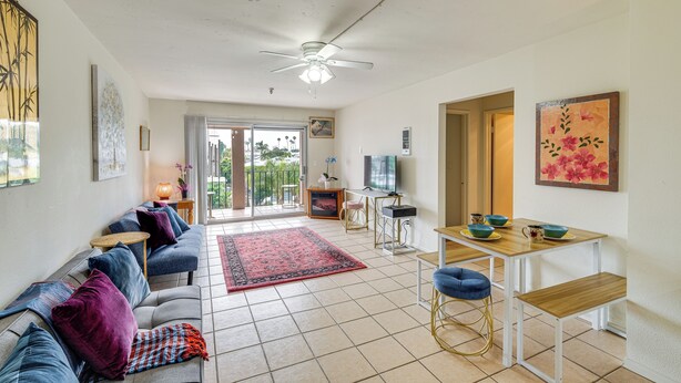 A spacious living room with a sofa, a dining table, and a ceiling fan. - Condo Near Hospitals & 1/2 Mi to Mission Bay! (San Diego)