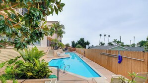 A swimming pool with steps leading into it, surrounded by a wooden fence and various plants. - Condo Near Hospitals & 1/2 Mi to Mission Bay! (San Diego)