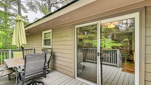 Une terrasse couverte avec une table et des chaises, une porte-fenêtre coulissante et une vue sur le jardin arrière.