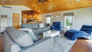 A spacious living room with a wooden ceiling, grey sofas, a white coffee table, and a blue armchair. - Lakefront Vacation Rental ~ 10 Mi to Shipshewana! (Howe)
