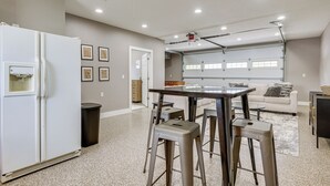 A modern kitchen with a refrigerator, bar stools, and a dining table. - Lakefront Vacation Rental ~ 10 Mi to Shipshewana! (Howe)