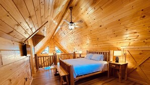 Ein Schlafzimmer in einer Holzhütte mit Schlafkoje, Holzwänden und geneigter Decke.