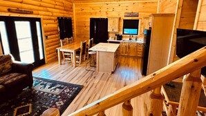 Ein Holzblockhaus-Innenraum mit Essbereich, Küche und einer Treppe.