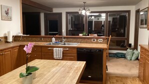 A modern kitchen with wooden cabinets, a built-in dishwasher, and a large window.
