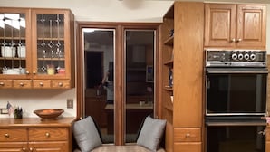 A kitchen with wooden cabinets, a built-in oven, and a seating area with cushions.
