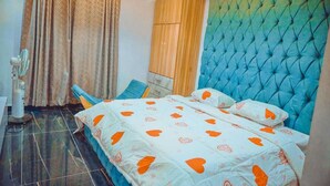 Una camera da letto con un letto, tende, una ventola e un armadio in legno.