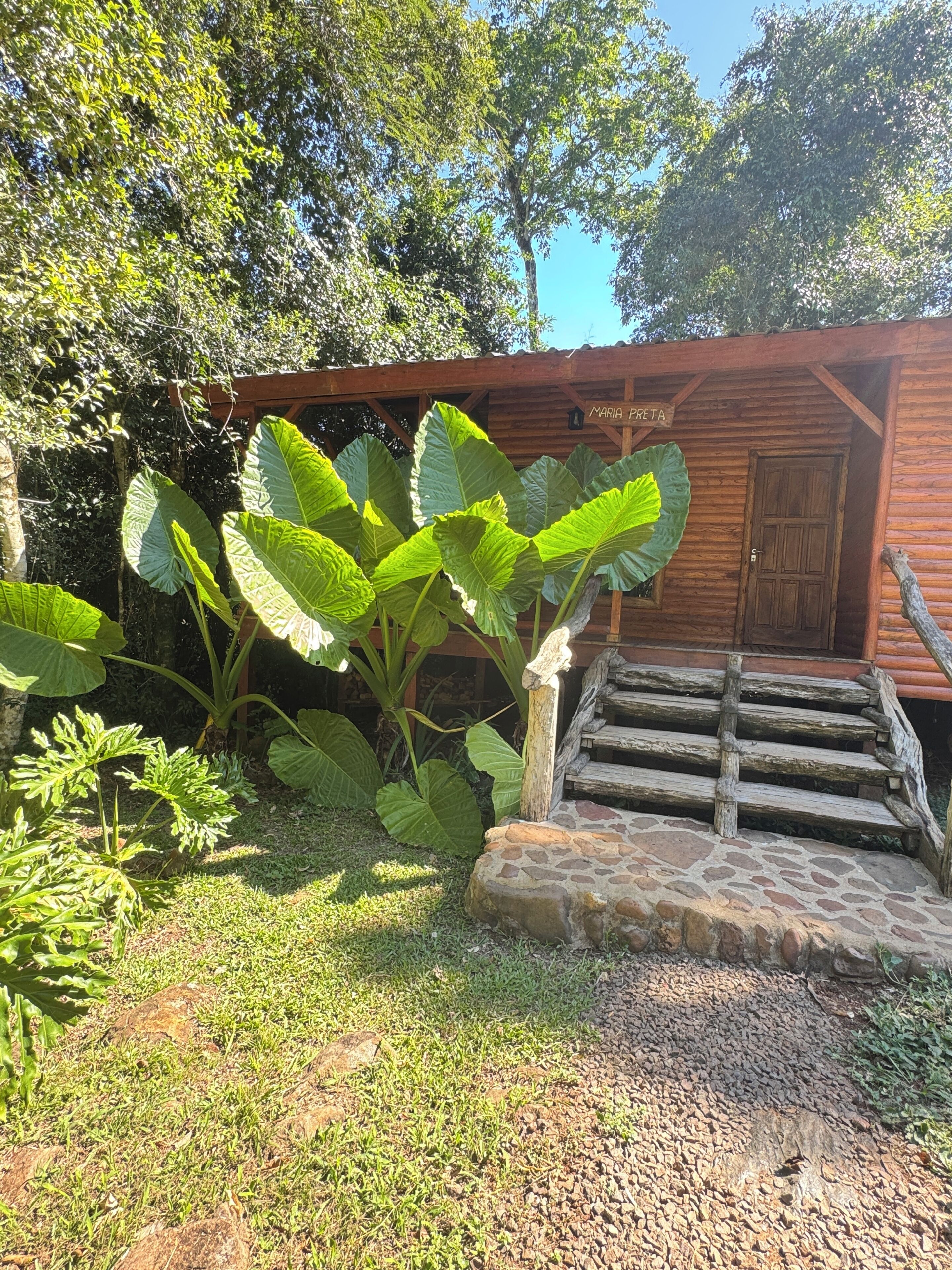 A wooden cabin with a stone staircase leading to a door labeled 'Maria Preta.'