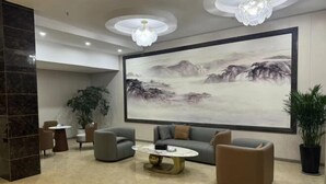 A modern lobby with a large painting, comfortable seating, and a chandelier.