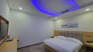 A hotel room with a bed, bedside tables, a flat-screen TV, and a painting on the wall.