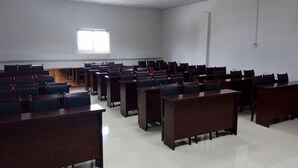 A classroom with rows of desks and chairs, a window, and a door.