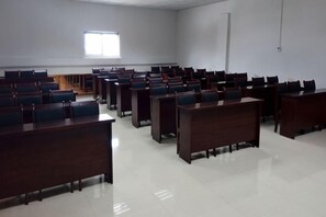 Un aula con filas de escritorios y sillas, una ventana y una puerta.