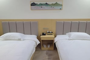 Habitación de hotel con dos camas, una mesita de noche con un teléfono y una lámpara, y un cuadro en la pared.