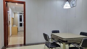 A dining area with a table and chairs, a chandelier, and a view into a room with a window and curtains.