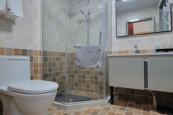 A bathroom with a toilet, a shower with a glass door, a sink, and a mirror.