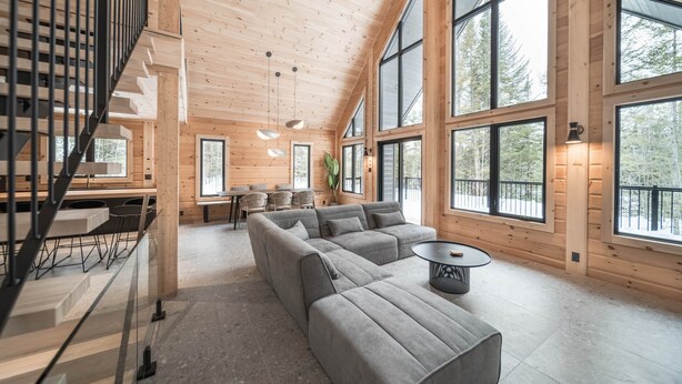A spacious living area with a large gray sectional sofa, a round coffee table, and a staircase leading to an upper level. - Le Mitik Kanata Tremblant (224) (Amherst)
