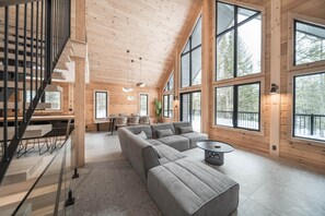 A spacious living area with a large gray sectional sofa, a round coffee table, and a staircase leading to an upper level.
