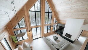 A spacious loft with large windows, a modern fireplace, and a cozy seating area. - Le Mitik Kanata Tremblant (224) (Amherst)