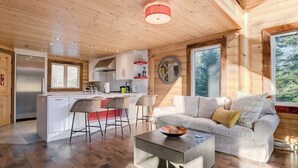 A modern log cabin interior with a kitchen, dining area, and living room. - Baycliff Kanata Tremblant (257) (Amherst)