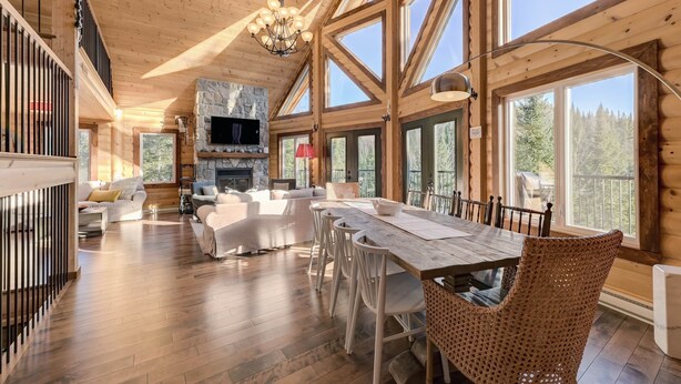 A spacious wooden interior with a dining area, high ceilings, and large windows. - Baycliff Kanata Tremblant (257) (Amherst)