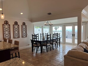 A spacious dining area with a dark wooden table and chairs, surrounded by a large window with a view of the outdoors. - San Clemente Paradise (San Clemente)