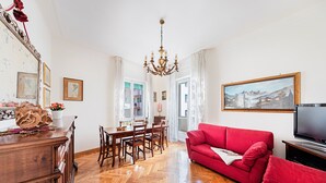 Ein geräumiges Wohnzimmer mit einem roten Sofa, einem Holzessttisch und einer Chandelier.