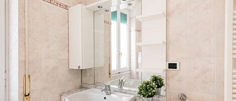 Une salle de bain moderne avec un lavabo en marbre, un grand miroir et un porte-serviettes.