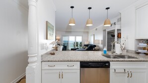 A modern kitchen with white cabinetry, granite countertops, a dishwasher, and pendant lighting. - "Beach Blessing" -Oceanfront Fun | Balcony (North Topsail Beach)