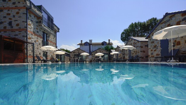 A swimming pool with lounge chairs and umbrellas, surrounded by stone buildings with balconies. - Agva Casa Rosa Bungalov Otel (Sile)