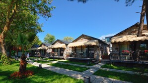 A courtyard with stone buildings, outdoor seating, and a pathway. - Agva Casa Rosa Bungalov Otel (Sile)