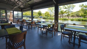 An outdoor dining area with tables and chairs, overlooking a river and greenery. - Agva Casa Rosa Bungalov Otel (Sile)