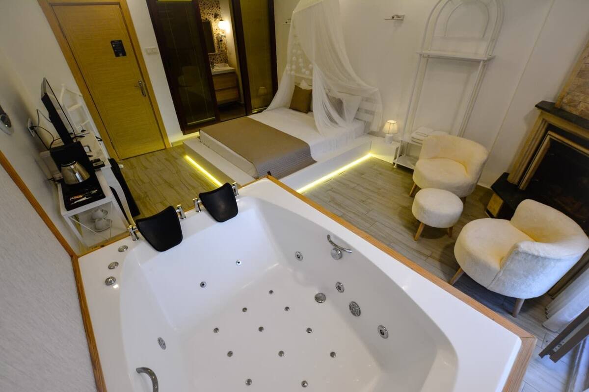 A modern bathroom with a large bathtub, a shower area, and a vanity with a mirror.