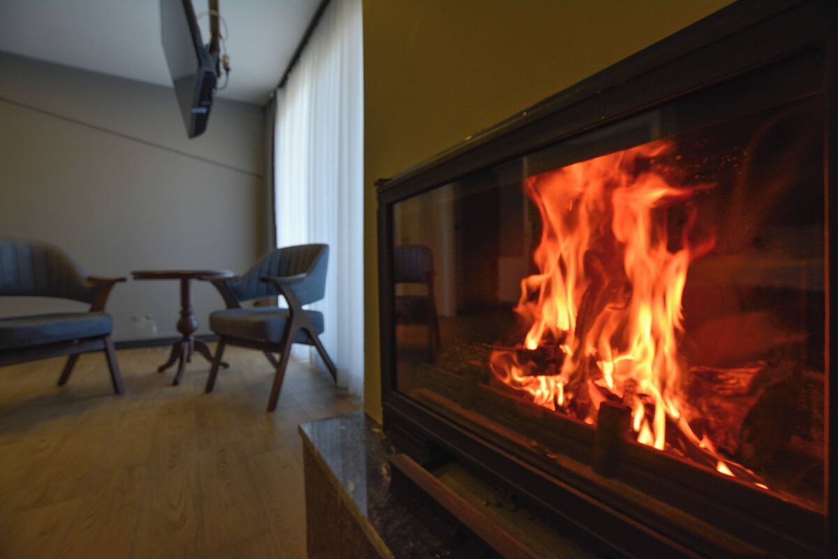 A room with a fireplace, two blue armchairs, and a wooden coffee table.