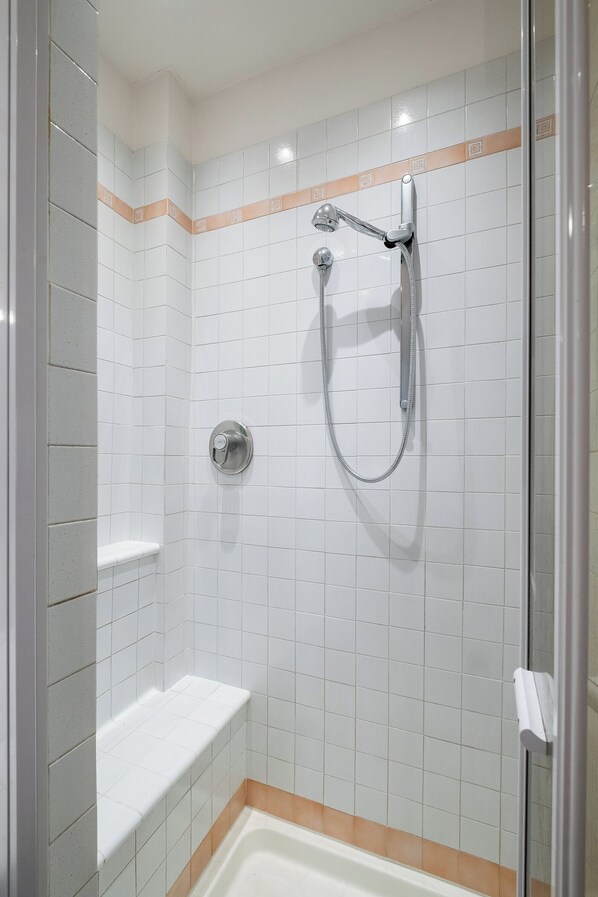 Une douche équipée d’un pommeau de douche à main et d’un robinet mural.