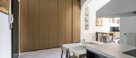 Una cocina moderna con un mueble grande de madera, una mesa de comedor con sillas y un arco que lleva a otra habitación.