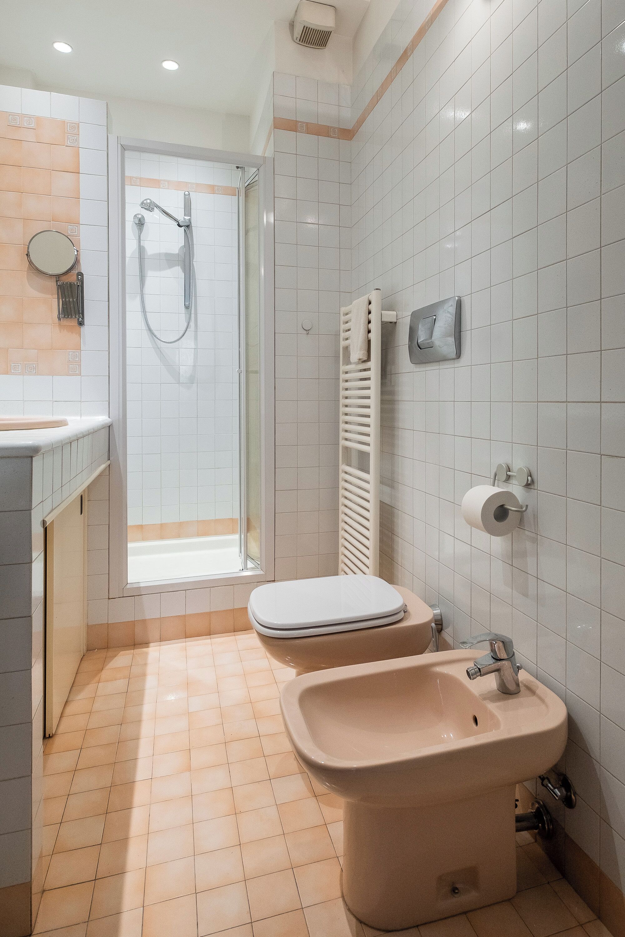 A modern bathroom with a shower, toilet, bidet, and a towel rack.
