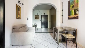 Un interior moderno con sofá, mesa de comedor y sillas, un arco que conduce a un pasillo y obras de arte en las paredes.