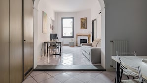 Una sala moderna con chimenea, un comedor y una cocina visibles a través de un arco.