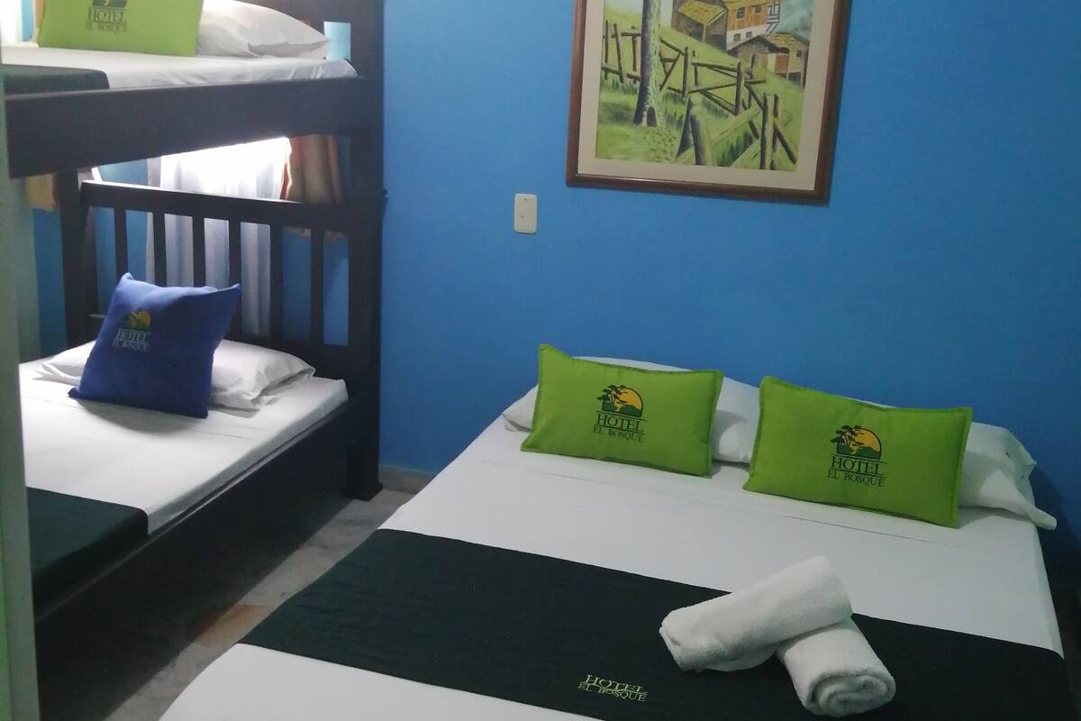 A hotel room with two beds, one with a bunk bed, and a painting on the wall.