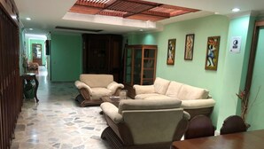 A spacious living area with a stone floor, a wooden ceiling, and a green wall. There are three beige sofas and a wooden coffee table. - HOTEL EL BOSQUE ARMENIA (Armenia)