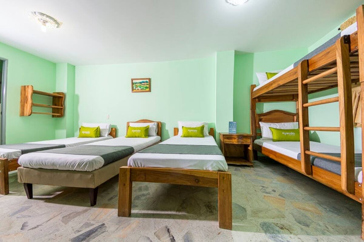 A room with four beds, two single and two double, wooden bunk beds, and a small table.