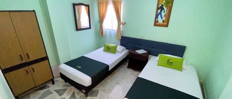 Habitación de hotel con dos camas, un armario, una mesita de noche y un cuadro en la pared.